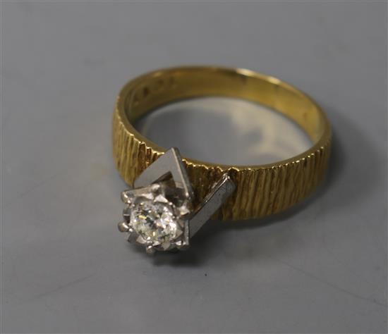 A textured 18ct gold and solitaire diamond ring, size Q.